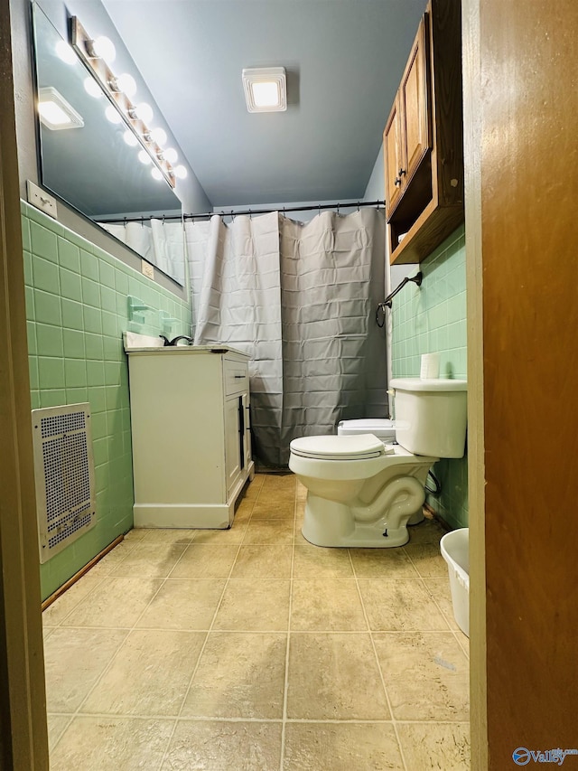 bathroom featuring tile patterned flooring, toilet, tile walls, and heating unit