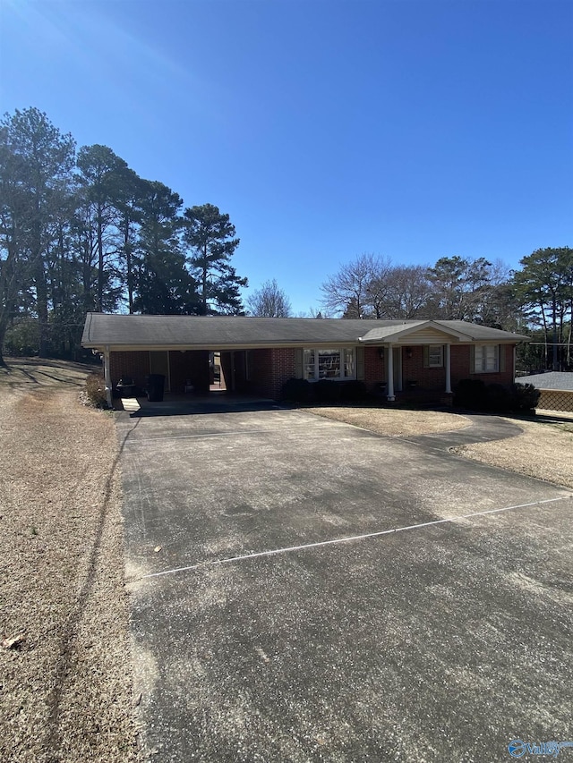 view of front of house with dirt driveway and a carport