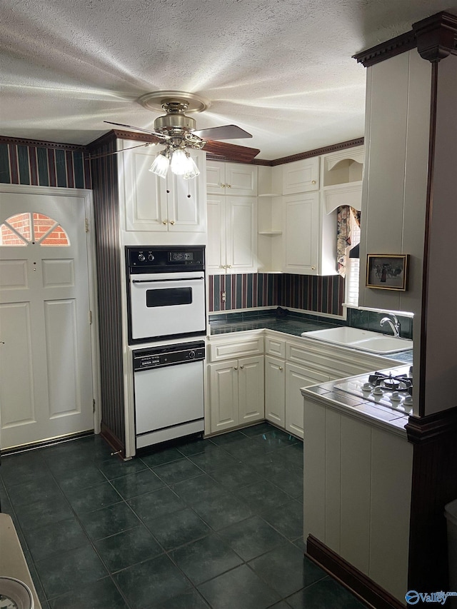 kitchen featuring a ceiling fan, white cabinets, a sink, a textured ceiling, and white appliances