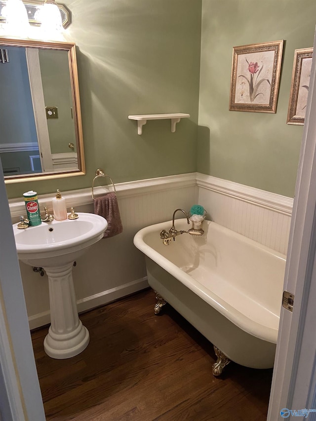 bathroom featuring a freestanding tub, wainscoting, and wood finished floors