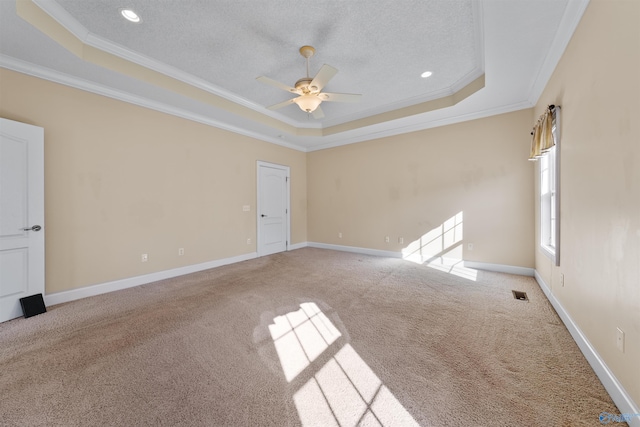 empty room featuring carpet, ceiling fan, a raised ceiling, crown molding, and a textured ceiling