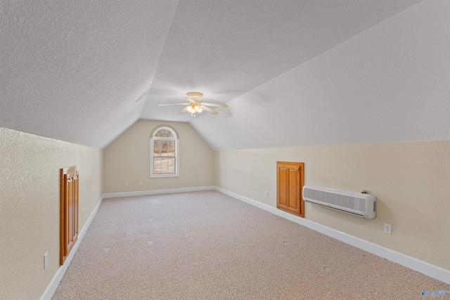 additional living space featuring lofted ceiling, ceiling fan, heating unit, a textured ceiling, and light carpet