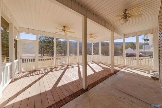 unfurnished sunroom featuring ceiling fan and a mountain view