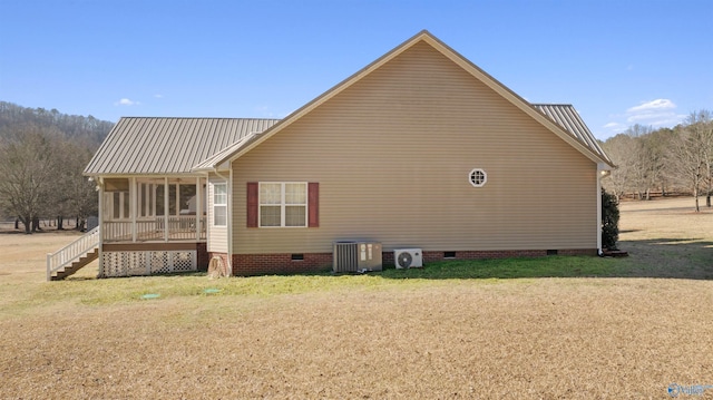 view of side of property with a yard, central AC, and a sunroom