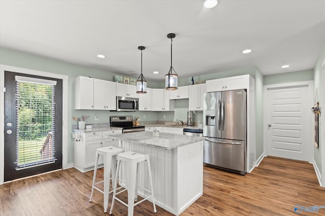kitchen featuring a sink, appliances with stainless steel finishes, white cabinets, and a center island