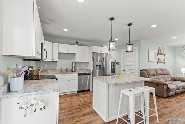 kitchen featuring appliances with stainless steel finishes, a center island, wood finished floors, open floor plan, and white cabinetry