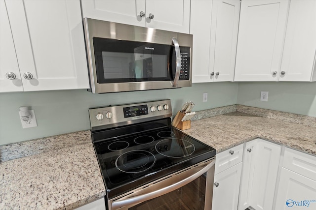 kitchen with white cabinets, light stone countertops, and appliances with stainless steel finishes