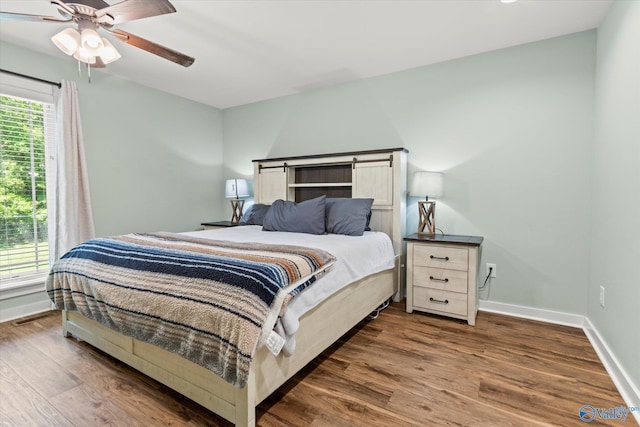 bedroom with baseboards, a ceiling fan, and dark wood finished floors