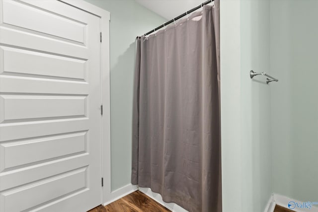 bathroom with baseboards, a shower with shower curtain, and wood finished floors
