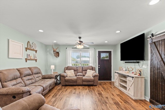 living area featuring light wood-style floors, a barn door, a ceiling fan, and recessed lighting