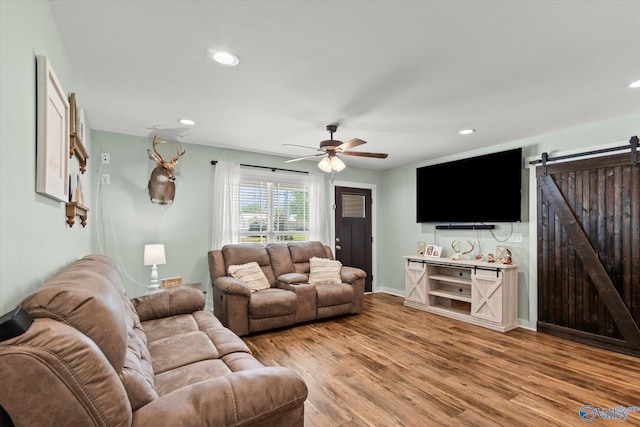 living area featuring baseboards, ceiling fan, recessed lighting, a barn door, and light wood-type flooring
