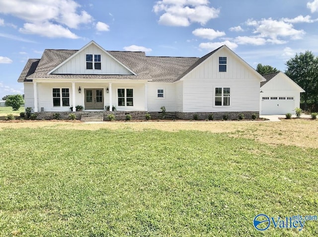 modern farmhouse featuring a front yard, covered porch, an outdoor structure, a garage, and board and batten siding