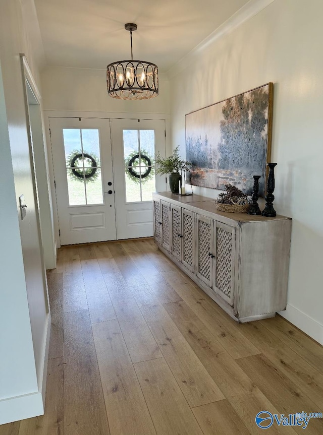 foyer featuring baseboards, light wood-type flooring, and an inviting chandelier