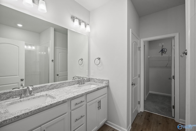 418 Tracer St, Huntsville, AL 35811 - bathroom with wood finished floors, double vanity, a spacious closet, a shower, and baseboards