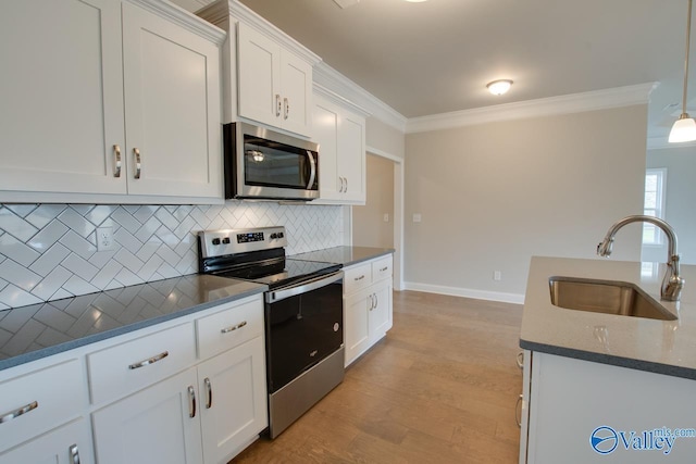 kitchen featuring pendant lighting, sink, white cabinetry, stainless steel appliances, and decorative backsplash