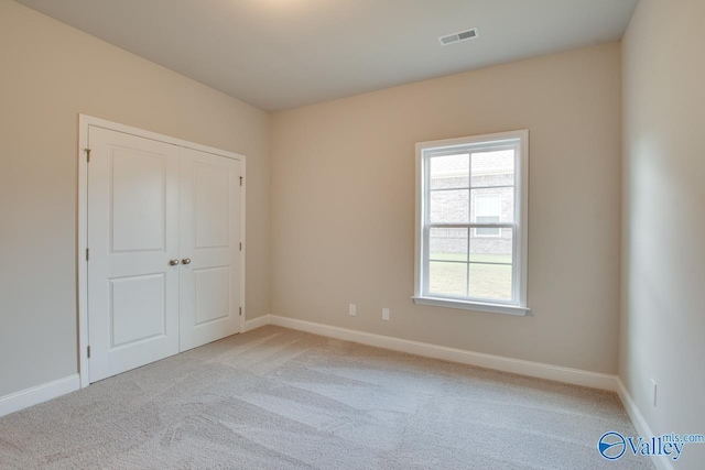 unfurnished bedroom with light carpet and a closet