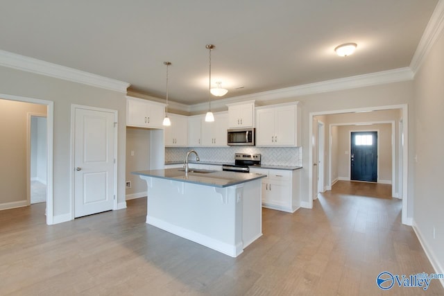 kitchen with sink, tasteful backsplash, appliances with stainless steel finishes, an island with sink, and white cabinets