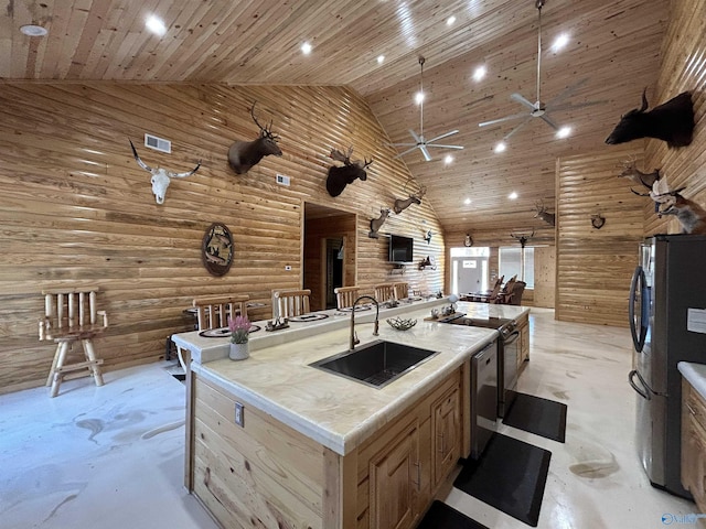 kitchen featuring sink, refrigerator, a center island with sink, light brown cabinetry, and log walls