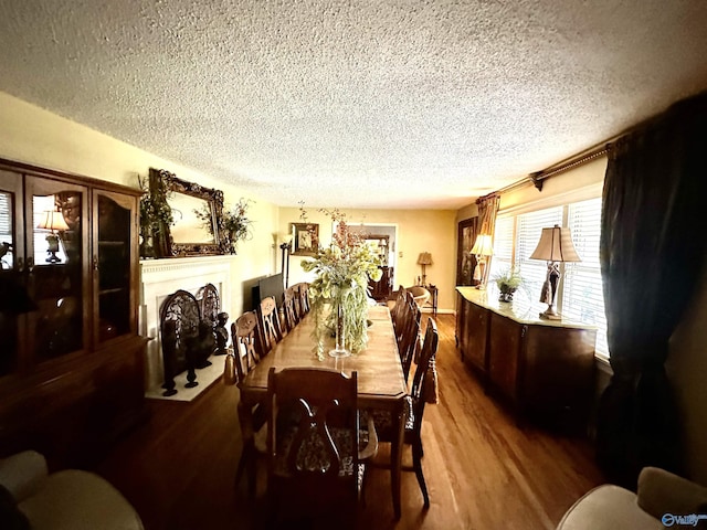 dining area with a textured ceiling, a fireplace, and wood finished floors