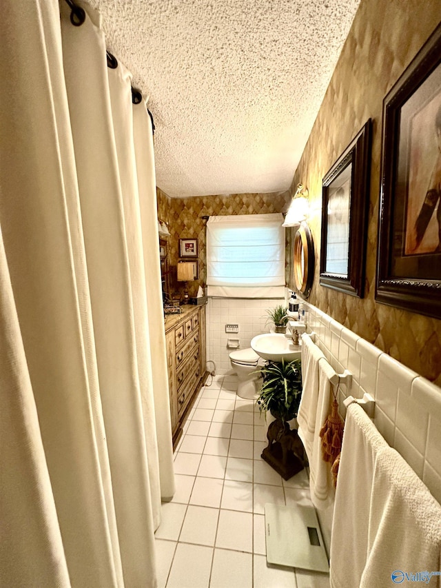 bathroom featuring tile walls, a wealth of natural light, toilet, a textured ceiling, and tile patterned floors