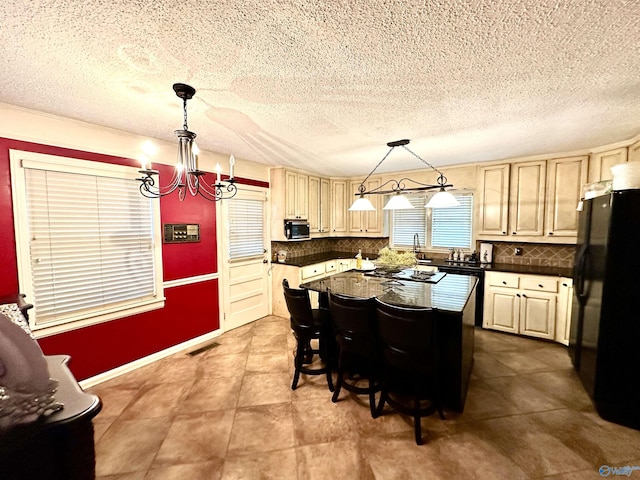 kitchen featuring dark countertops, a center island, freestanding refrigerator, and pendant lighting