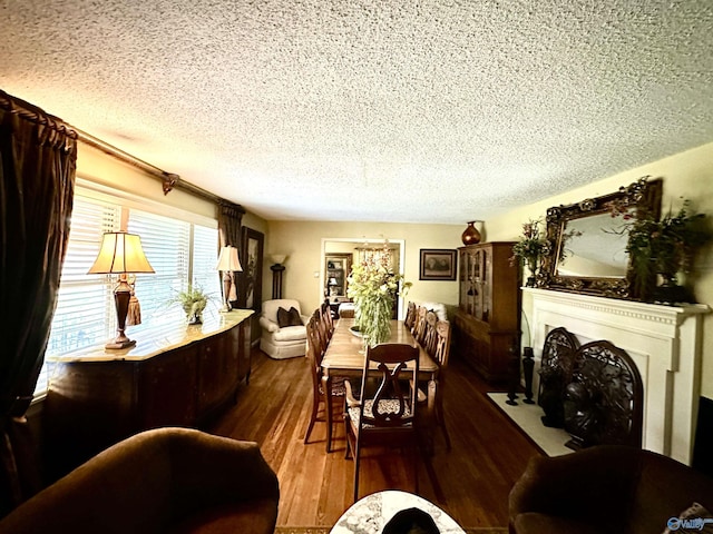 dining area with a textured ceiling, dark wood-style flooring, and a fireplace with flush hearth