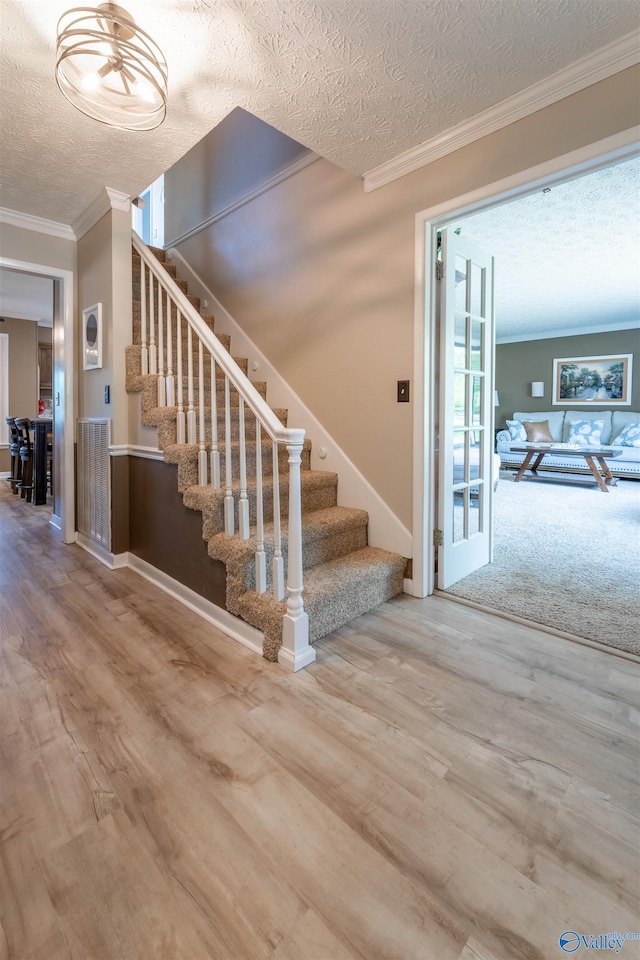 stairway featuring ornamental molding, a textured ceiling, and wood finished floors