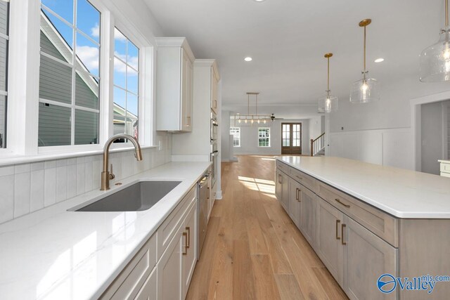 kitchen featuring decorative light fixtures, sink, white cabinets, light hardwood / wood-style floors, and a spacious island