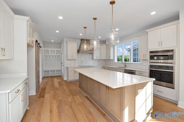 kitchen featuring a spacious island, white cabinetry, stainless steel appliances, and a barn door