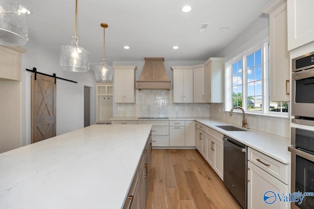 kitchen with premium range hood, sink, hanging light fixtures, stainless steel appliances, and light stone countertops