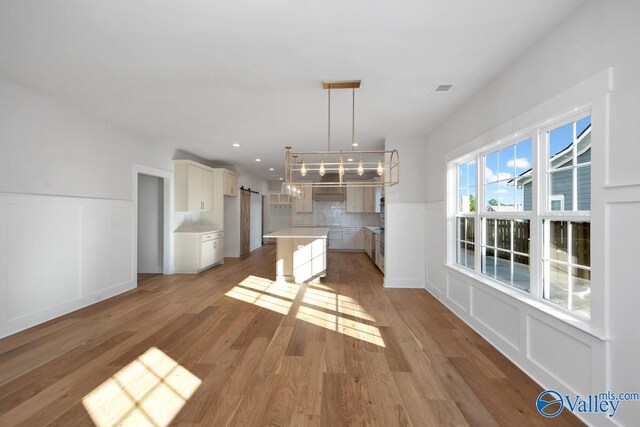 kitchen featuring white cabinetry, decorative light fixtures, light hardwood / wood-style floors, and a center island