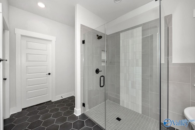 bathroom featuring tile patterned flooring, a shower with door, and tile walls