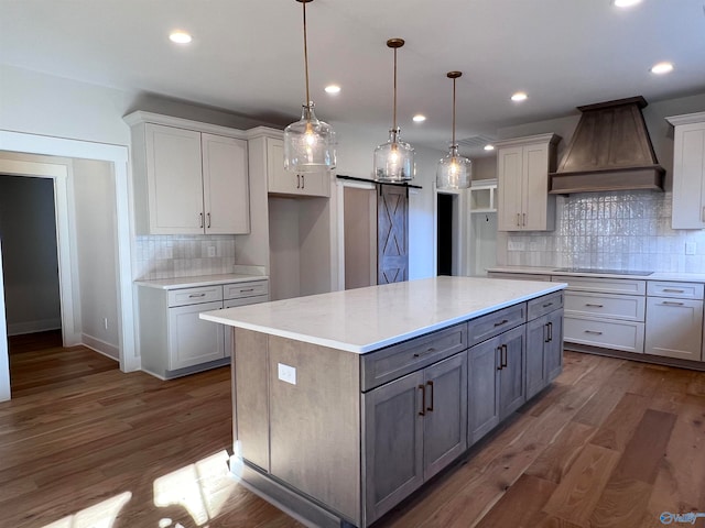 kitchen featuring a kitchen island, dark hardwood / wood-style floors, decorative light fixtures, custom exhaust hood, and a barn door