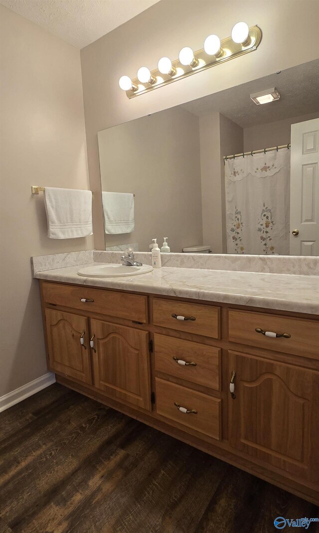 113 Sycamore Pl, Athens, AL 35611 - bathroom featuring double vanity, wood finished floors, a textured ceiling, and baseboards