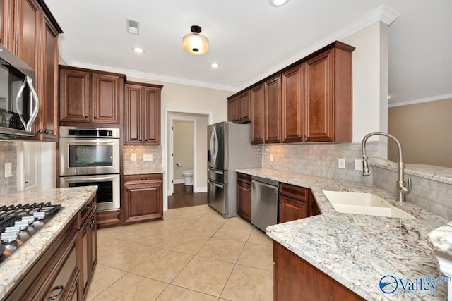 kitchen with light stone counters, light tile patterned floors, stainless steel appliances, visible vents, and a sink