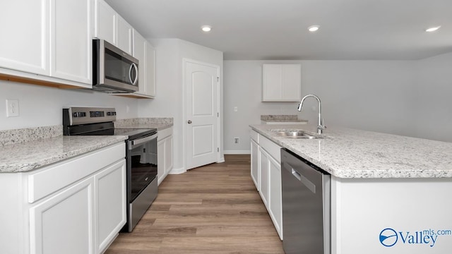 kitchen with white cabinetry, sink, stainless steel appliances, and an island with sink