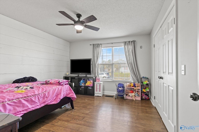 bedroom featuring ceiling fan, a closet, dark wood-type flooring, and a textured ceiling