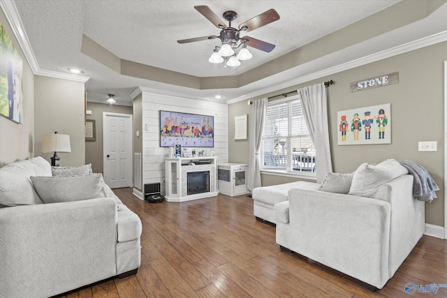 living room with dark wood-type flooring, a textured ceiling, and ornamental molding