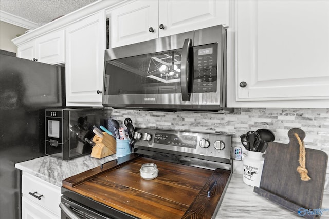 kitchen featuring backsplash, white cabinetry, stainless steel appliances, and a textured ceiling