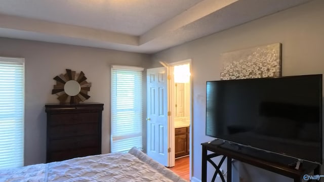 bedroom with ensuite bathroom and light wood-style floors