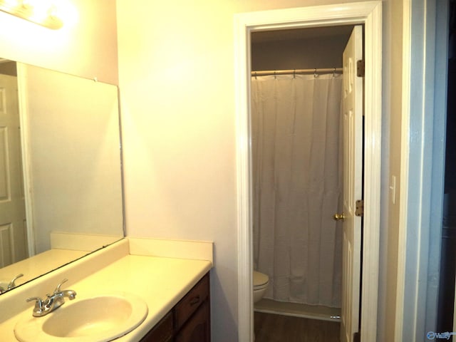 bathroom with a shower with curtain, vanity, toilet, and wood finished floors