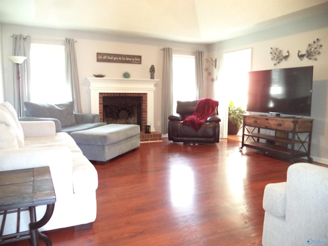 living area with a brick fireplace and wood finished floors