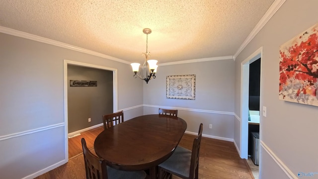 dining room with ornamental molding, a notable chandelier, a textured ceiling, and wood finished floors