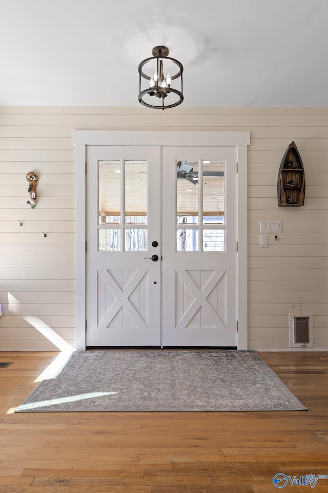 doorway to outside with wood finished floors and a notable chandelier