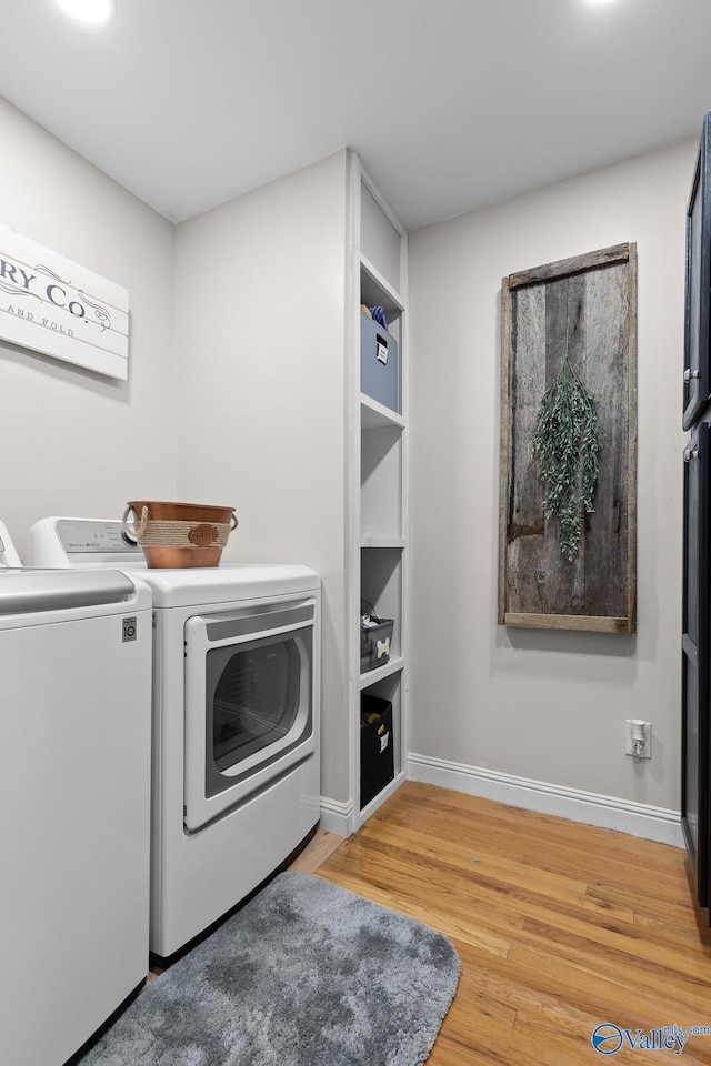 laundry room with laundry area, baseboards, wood finished floors, and independent washer and dryer