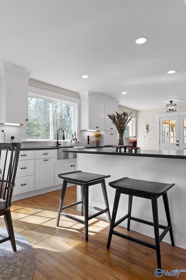 kitchen featuring dark countertops, a sink, a kitchen bar, and white cabinets