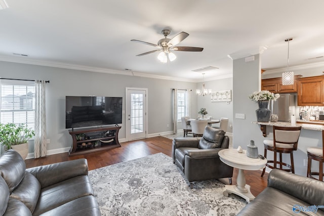 living room with dark hardwood / wood-style flooring, a wealth of natural light, crown molding, and ceiling fan with notable chandelier