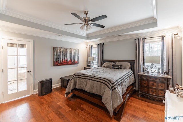 bedroom with hardwood / wood-style floors, a tray ceiling, ceiling fan, and crown molding