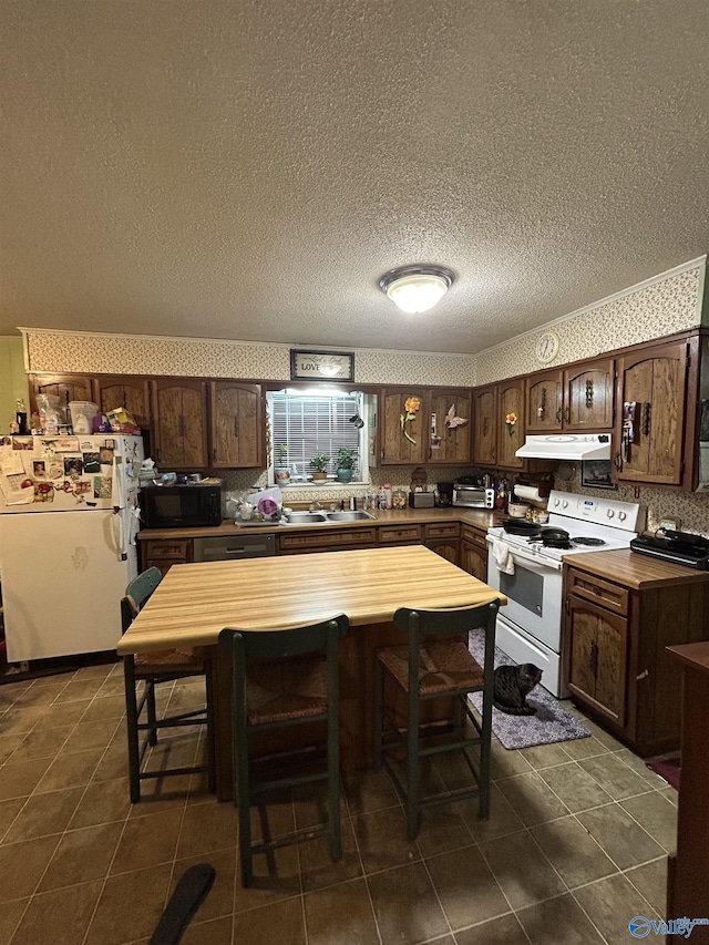 kitchen featuring sink, white appliances, dark tile patterned floors, butcher block counters, and dark brown cabinets