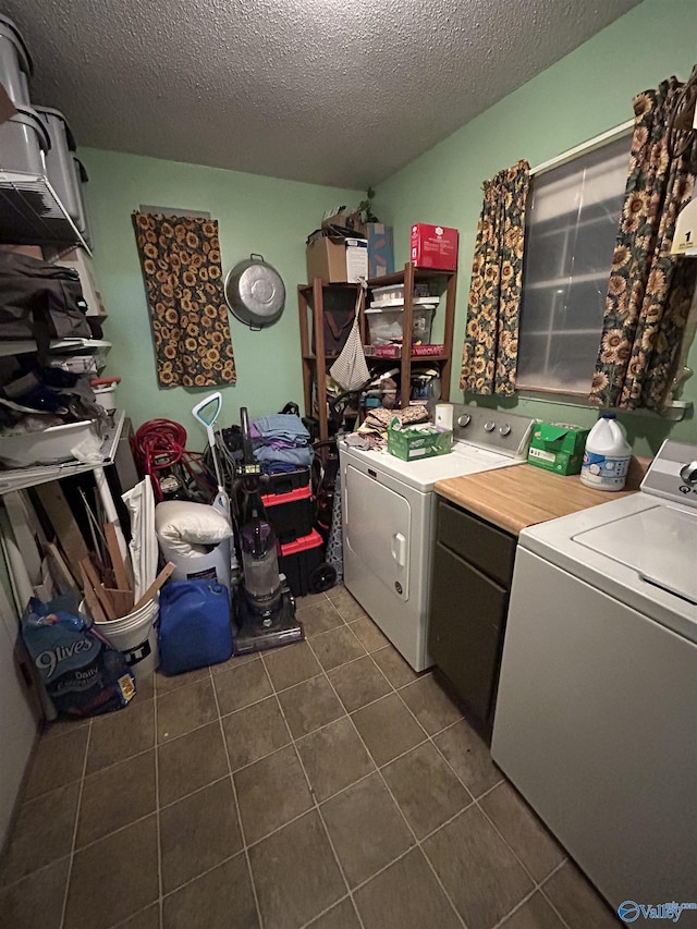 laundry room with cabinets, separate washer and dryer, dark tile patterned flooring, and a textured ceiling